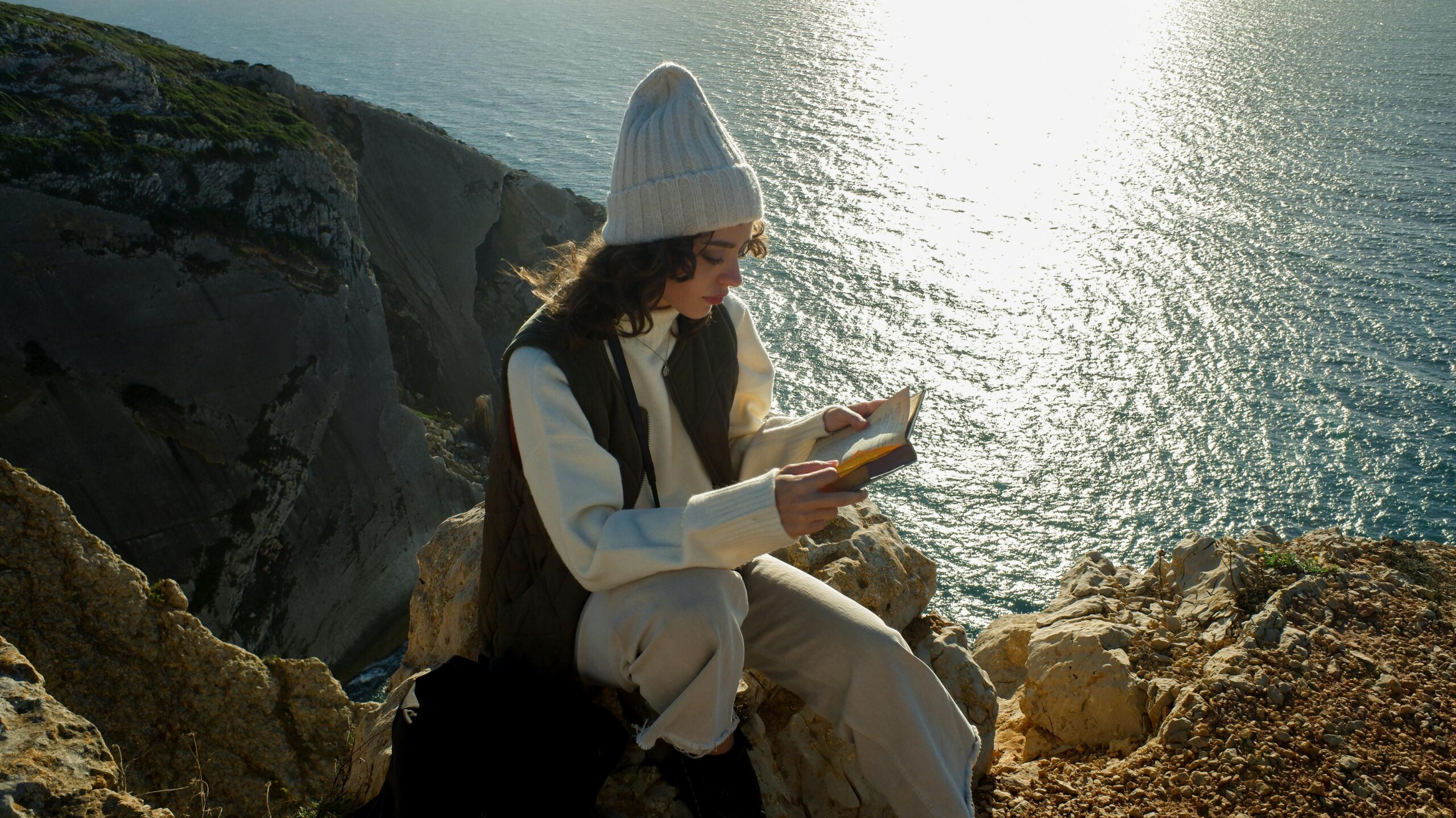 Woman reads book by water